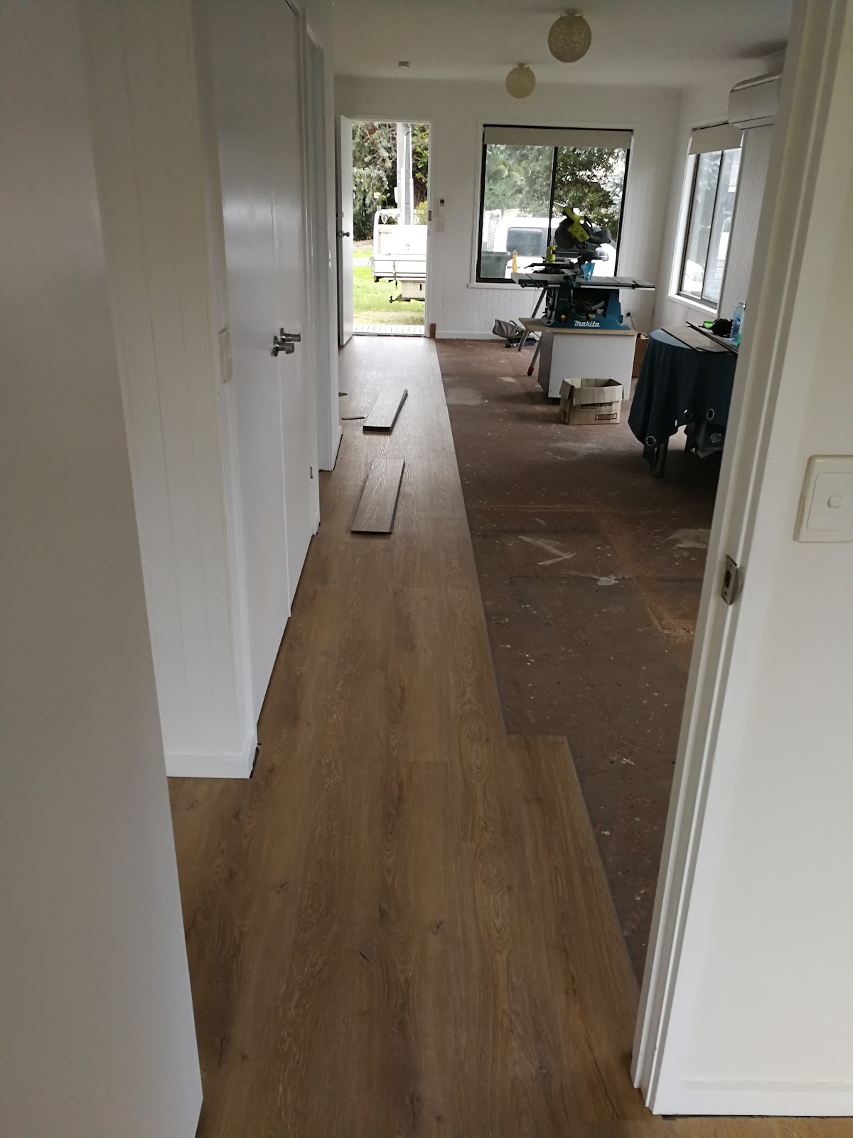 Hallway with the new floor half laid and tools at the far end