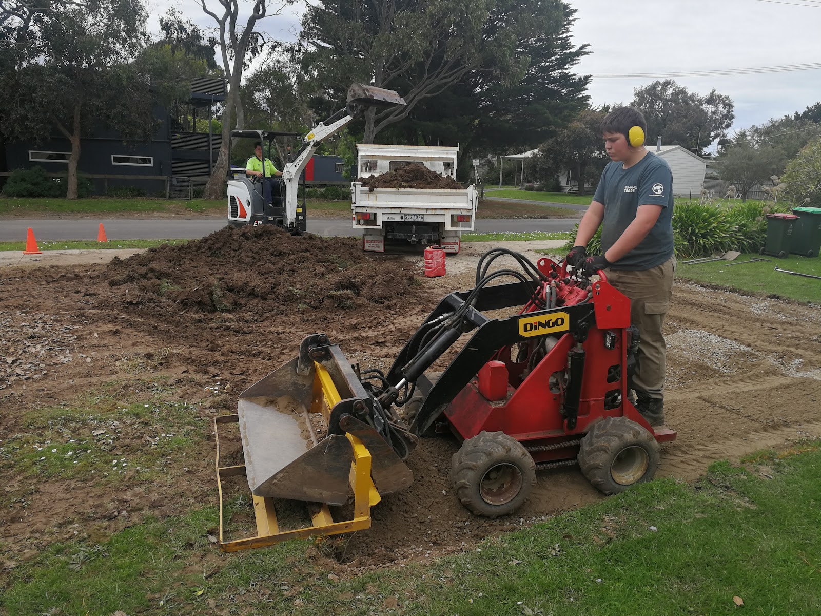 One of the Saric crew levelling a block with the mini loader, excavator and tipper behind