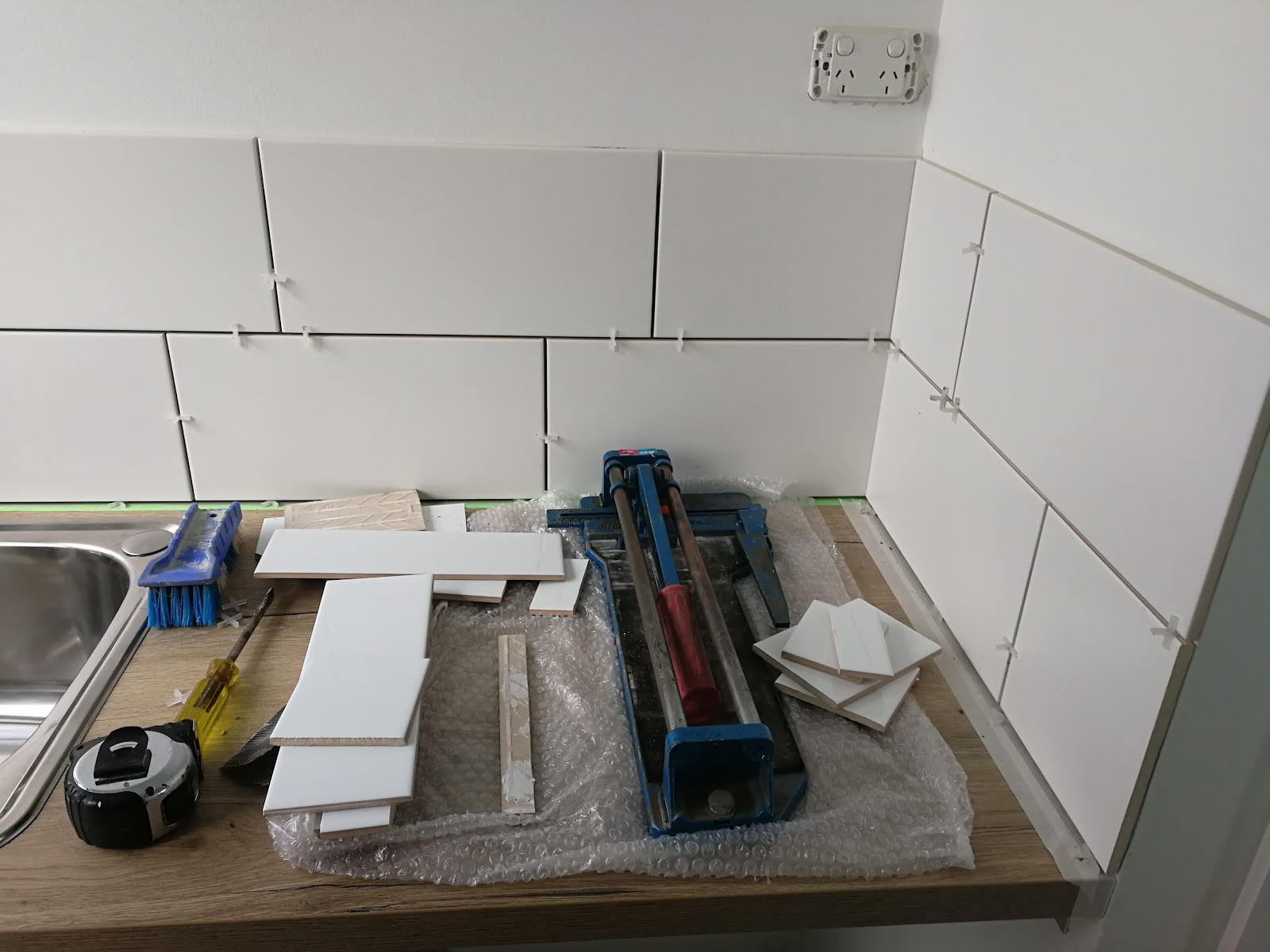 Splashback tiles going on with the tile cutter on the bench