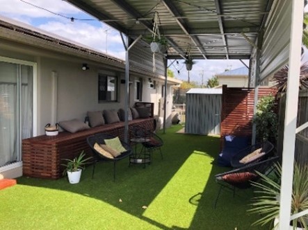 A finished backyard with covered outdoor area and lawn